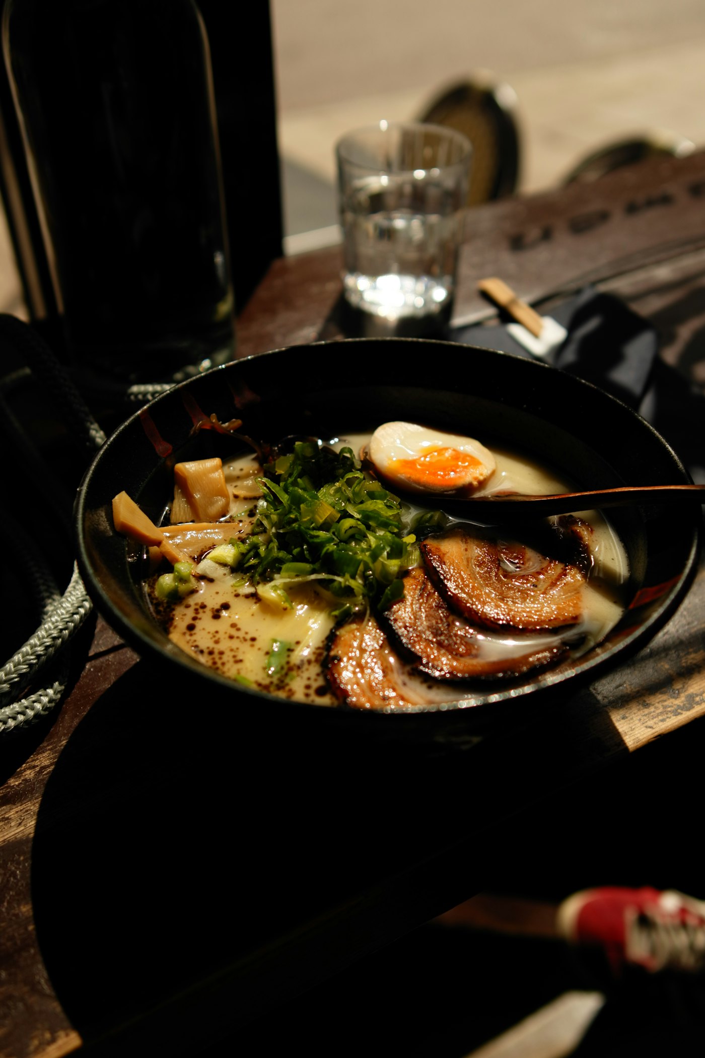 Bol de tonkotsu con chashu flameado, cebolleta, menma y huevo marinado sobre una barra de madera